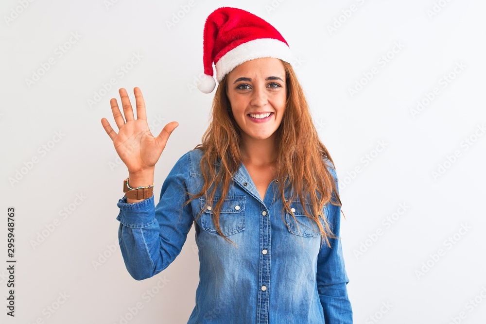 Young beautiful redhead woman wearing christmas hat over isolated background showing and pointing up with fingers number five while smiling confident and happy. Young beautiful redhead woman wearing christmas hat over isolated background showing and pointing up with fingers number five while smiling confident and happy.