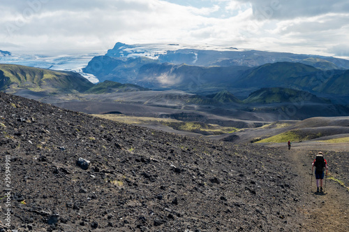 Icelandic lava desert landscape with Tindfjallajokull glacier and two hikers on Laugavegur hiking trail. Fjallabak Nature Reserve, Iceland. Summer blue sky, clouds. photo