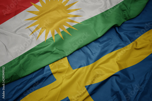 Foto waving colorful flag of sweden and national flag of kurdistan.