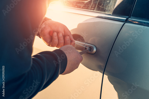 Car robber or thief trying to break auto door lock, close up. Car theft concept photo