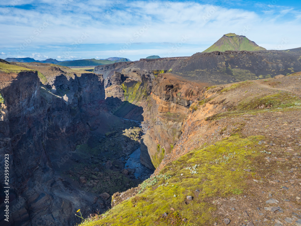 View on majestic Markarfljotsgljufur Canyon gorge and river with green hills and Hattafell mountain near Botnar camp at Fjallabak Nature Reserve in Highlands of Iceland, blue sky background