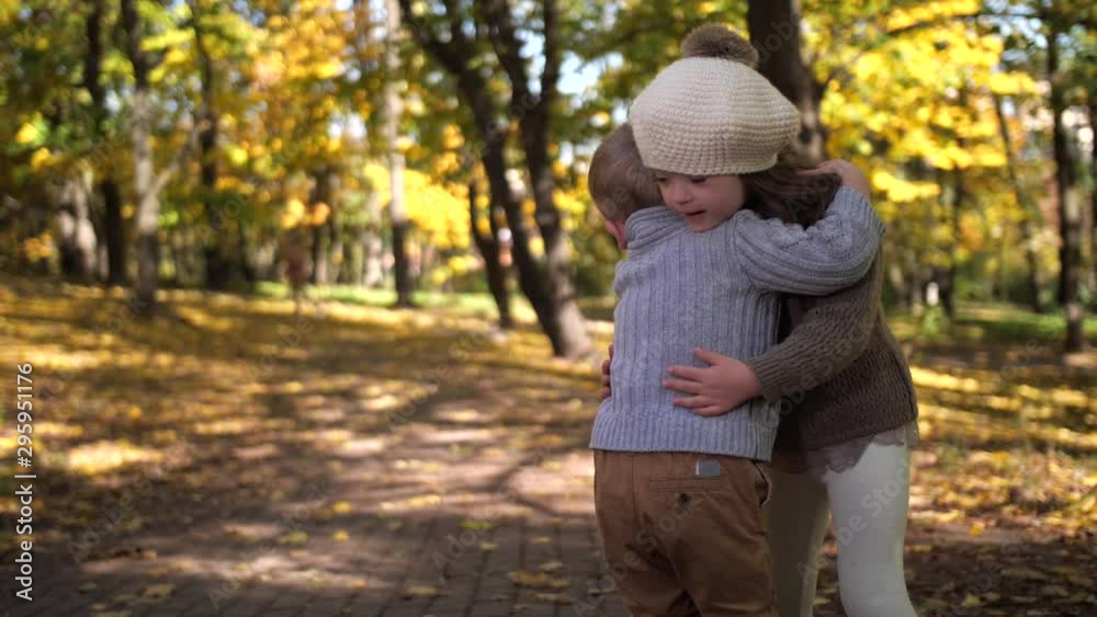 Close-up of joyful toddler siblings cuddling in autumn park, little boy hugging and kissing his older sister with down syndrome. Happy children expressing mutual love while spending freetime outdoors Close-up of joyful toddler siblings cuddling in autumn park, little boy hugging and kissing his older sister with down syndrome. Happy children expressing mutual love while spending freetime outdoors