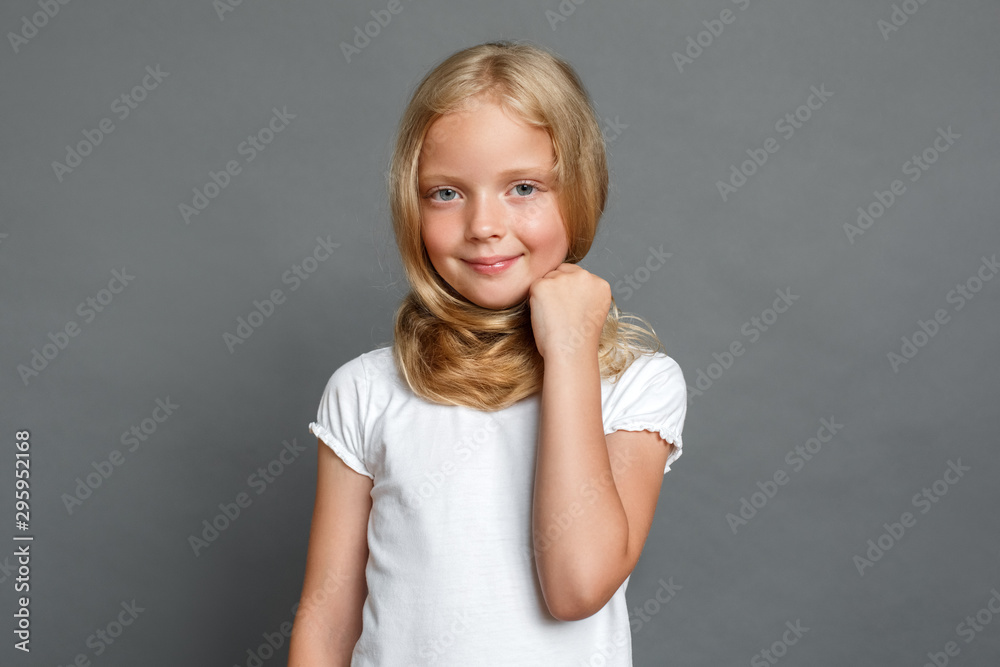 Little girl with long hair standing isolated on grey looking camera joyful Little girl with long hair standing isolated on grey looking camera joyful