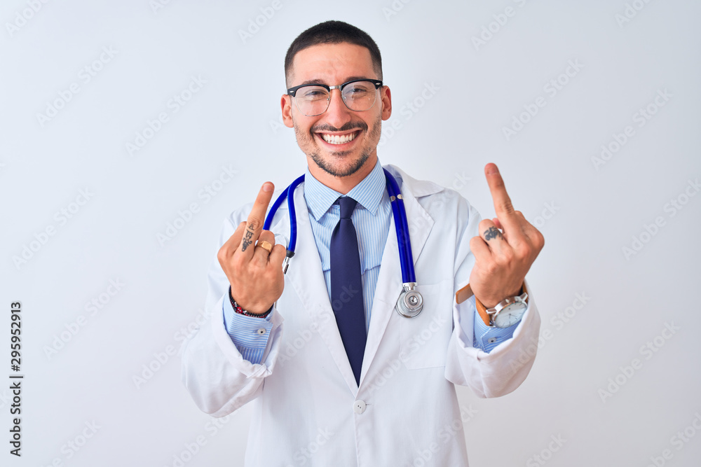 Young doctor man wearing stethoscope over isolated background Showing middle finger doing fuck you bad expression, provocation and rude attitude. Screaming excited Young doctor man wearing stethoscope over isolated background Showing middle finger doing fuck you bad expression, provocation and rude attitude. Screaming excited