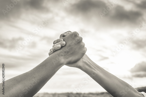 Strong hands coming together grasping one another, helping hand. People working together, unity, teamwork 