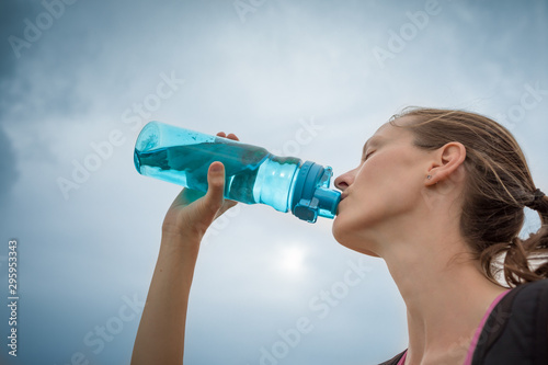 Young female outdoors drinking water. 