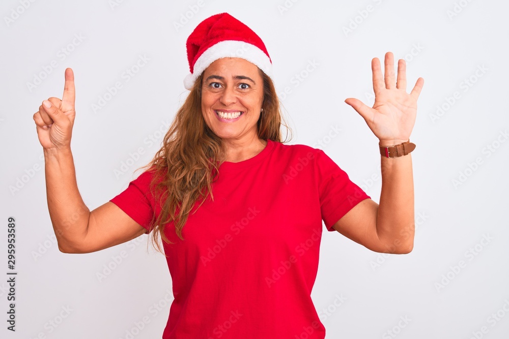 Middle age mature woman wearing christmas hat over isolated background showing and pointing up with fingers number six while smiling confident and happy. Middle age mature woman wearing christmas hat over isolated background showing and pointing up with fingers number six while smiling confident and happy.