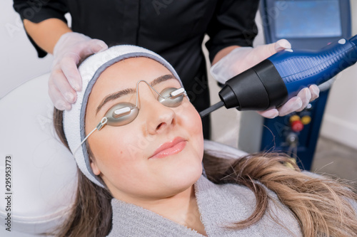 CO2 fractional ablative laser being used for skin rejuvenation (skin resurfacing) as a medical cosmetic procedure in a beauty laser clinic. Female patient wearing goggles, with beauty laser technician photo