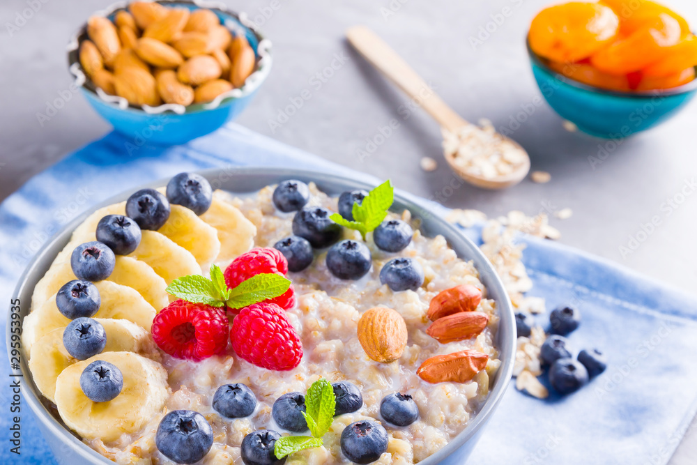 Healthy homemade oatmeal with berries and nuts for breakfast. Oatmeal with fruits, nuts and honey. Oatmeal with blueberries, banana and raspberries Healthy homemade oatmeal with berries and nuts for breakfast. Oatmeal with fruits, nuts and honey. Oatmeal with blueberries, banana and raspberries