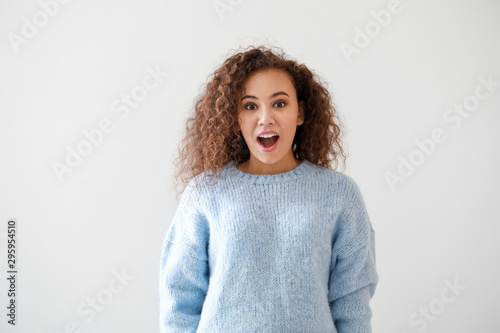 Portrait of surprised young African-American woman on light background © Pixel-Shot