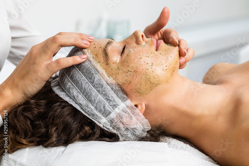 Beautiful woman receiving facial mask with rejuvenating effects in spa beauty salon. photo