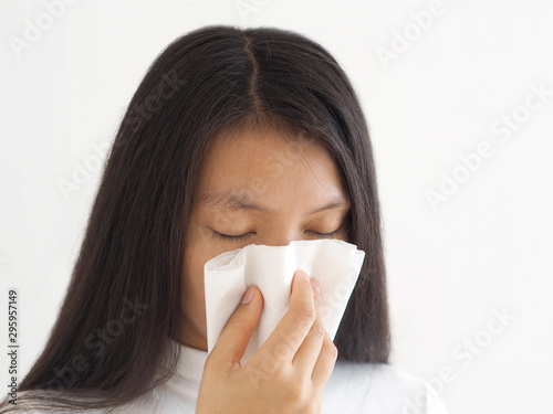 common cold and flu or influenza epstein barr virus or EBV and sinusitis, nasal polyp and asthma in woman and she hold white paper napkin close on nose on white background use for health care concept. photo