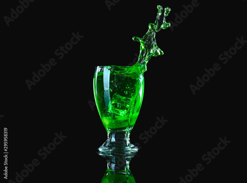 Glass of tasty cocktail with splashes on dark background