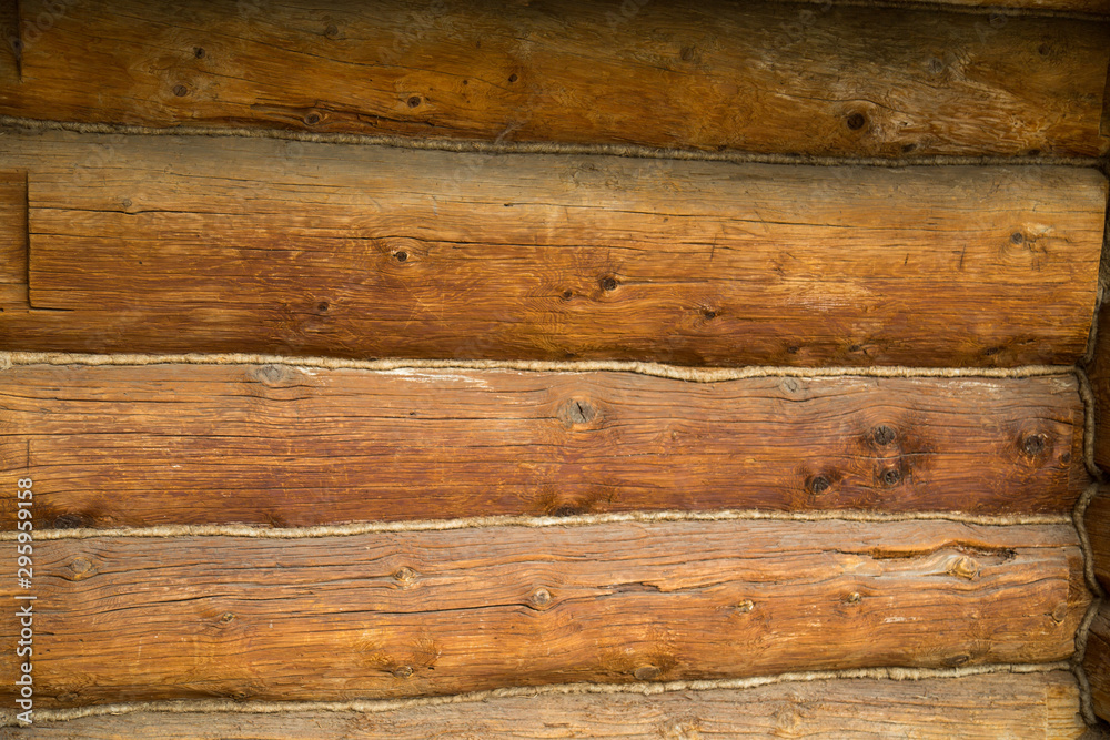 The wall is old, the background of huge old logs of coniferous species with seams, insulated with oakum. Backgrounds, structures, designs. The wall is old, the background of huge old logs of coniferous species with seams, insulated with oakum. Backgrounds, structures, designs.