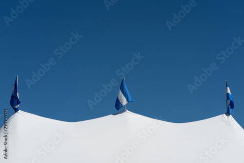 colorblock blue and white theme with white wedding tent blue sky and striped flags © Rosemarie Mosteller