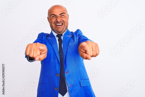 Middle age businessman wearing suit standing over isolated white background pointing to you and the camera with fingers, smiling positive and cheerful