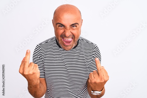 Middle age handsome man wearing striped navy t-shirt over isolated white background Showing middle finger doing fuck you bad expression, provocation and rude attitude. Screaming excited