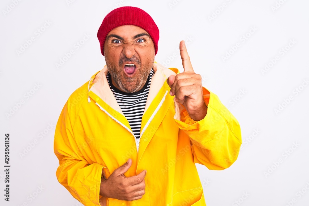 Middle age man wearing rain coat and woolen hat standing over isolated white background pointing finger up with successful idea. Exited and happy. Number one. Middle age man wearing rain coat and woolen hat standing over isolated white background pointing finger up with successful idea. Exited and happy. Number one.