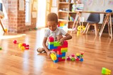 Beautiful african american toddler playing with building blocks smiling at kindergarten