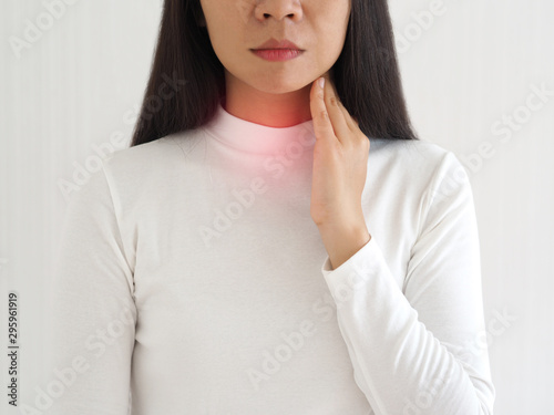 thyroid gland,hyperthyroidism and tonsillolith or tonsil stones and laryngeal cancer in asian woman. She use hand touching neck on isolated white background using for health care concept. photo
