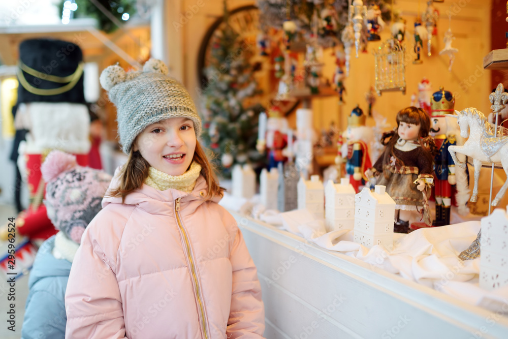 Young girl looking at Christmas dolls and decorations sold at Christmas market in Vilnius, Lithuania.