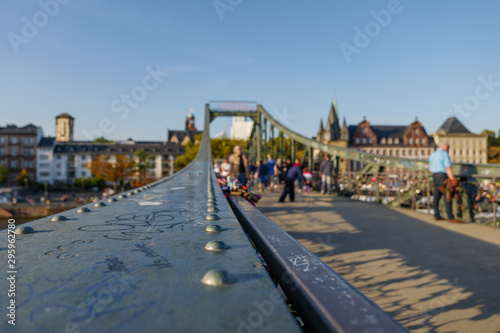 Close up view on steel handrail of balustrade on footbridge called Iron Bridge, Eiserner Steg, cross Main River in Frankfurt, Germany and blur background crowd of tourists.