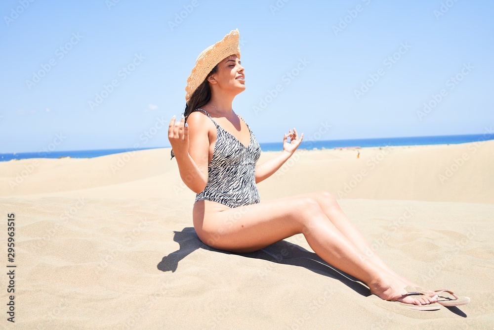 Young beautiful woman sunbathing and relaxing sitting on the sand doing yoga poses at maspalomas dunes bech Young beautiful woman sunbathing and relaxing sitting on the sand doing yoga poses at maspalomas dunes bech