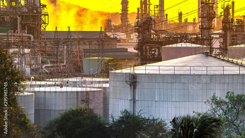 Oil and gas industrial refinery zone,Detail of equipment oil pipeline steel with valve from large oil storage tank at sunset.