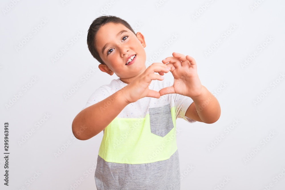 Beautiful kid boy wearing casual t-shirt standing over isolated white background smiling in love showing heart symbol and shape with hands. Romantic concept. Beautiful kid boy wearing casual t-shirt standing over isolated white background smiling in love showing heart symbol and shape with hands. Romantic concept.
