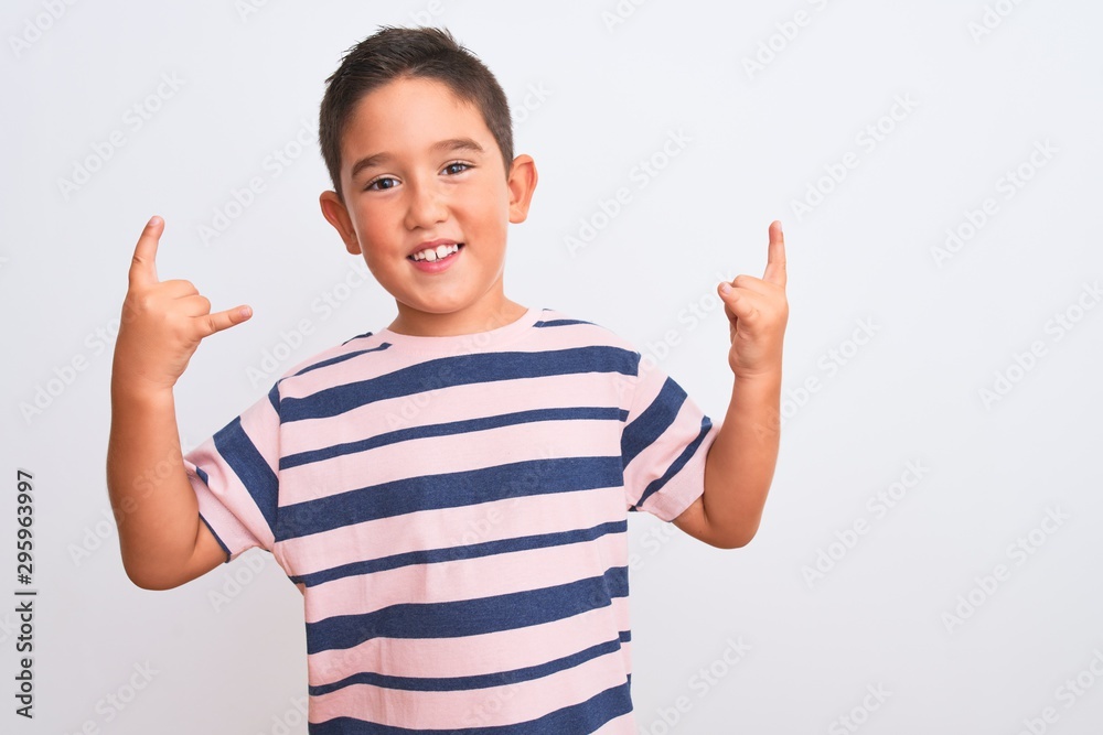 Beautiful kid boy wearing casual striped t-shirt standing over isolated white background shouting with crazy expression doing rock symbol with hands up. Music star. Heavy concept.