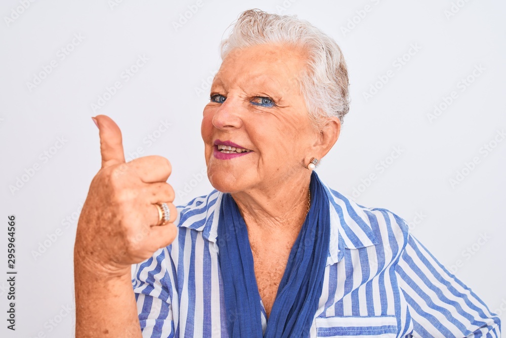 Senior grey-haired woman wearing blue striped shirt standing over isolated white background happy with big smile doing ok sign, thumb up with fingers, excellent sign Senior grey-haired woman wearing blue striped shirt standing over isolated white background happy with big smile doing ok sign, thumb up with fingers, excellent sign