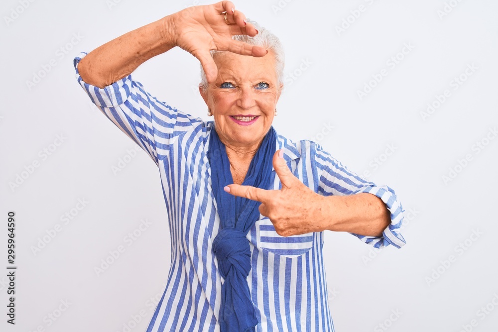Senior grey-haired woman wearing blue striped shirt standing over isolated white background smiling making frame with hands and fingers with happy face. Creativity and photography concept.