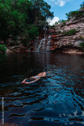 Mujer relajada en lago, al pie de una cascada