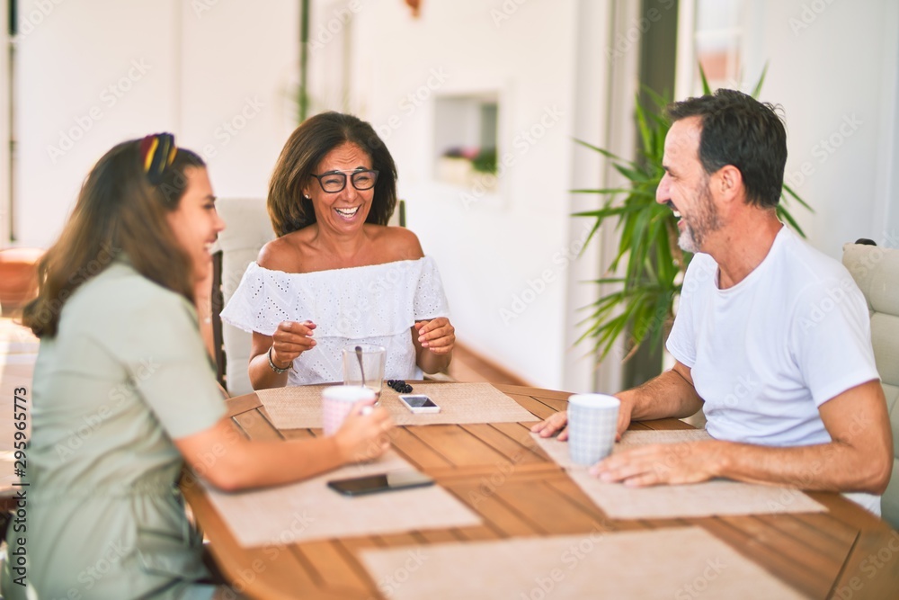 Beautiful family sitting on terrace drinking cup of coffee speaking and smiling Beautiful family sitting on terrace drinking cup of coffee speaking and smiling