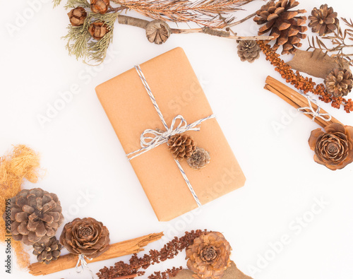 Centered kraft paper rustic gift box isolated on white background with autumn decorations: pine cones, cinnamon sticks, leaves and branches / For weddings, fall, winter and holidays