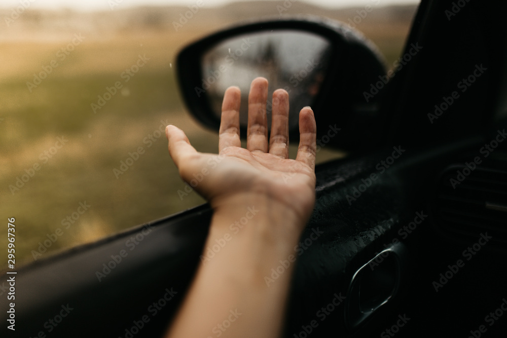 Hand touching rain drops. Mirror seen through the glass. Wet car window. Close up rain drop. Car view see the mirror. Rainy day.