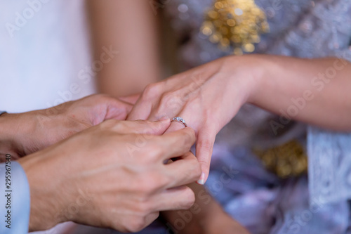 Wedding rings. He Put the Wedding Ring on Her. Close up Groom Put the Ring on bride. thai wedding ceremony and thai wedding decoration. Groom Put the Ring on bride's finger.