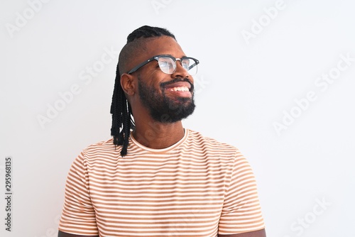 African american man wearing striped t-shirt and glasses over isolated white background looking away to side with smile on face, natural expression. Laughing confident. © Krakenimages.com