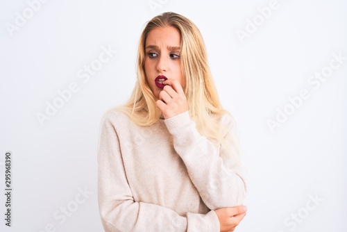 Young beautiful woman wearing turtleneck sweater standing over isolated white background looking stressed and nervous with hands on mouth biting nails. Anxiety problem.