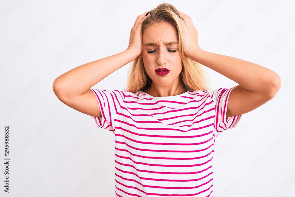 Young beautiful woman wearing pink striped t-shirt standing over isolated white background suffering from headache desperate and stressed because pain and migraine. Hands on head. Young beautiful woman wearing pink striped t-shirt standing over isolated white background suffering from headache desperate and stressed because pain and migraine. Hands on head.