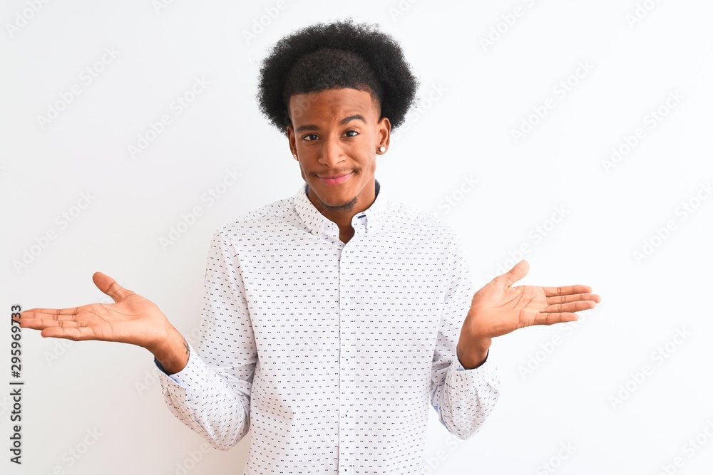 Young african american man wearing elegant shirt standing over isolated white background clueless and confused expression with arms and hands raised. Doubt concept. Young african american man wearing elegant shirt standing over isolated white background clueless and confused expression with arms and hands raised. Doubt concept.