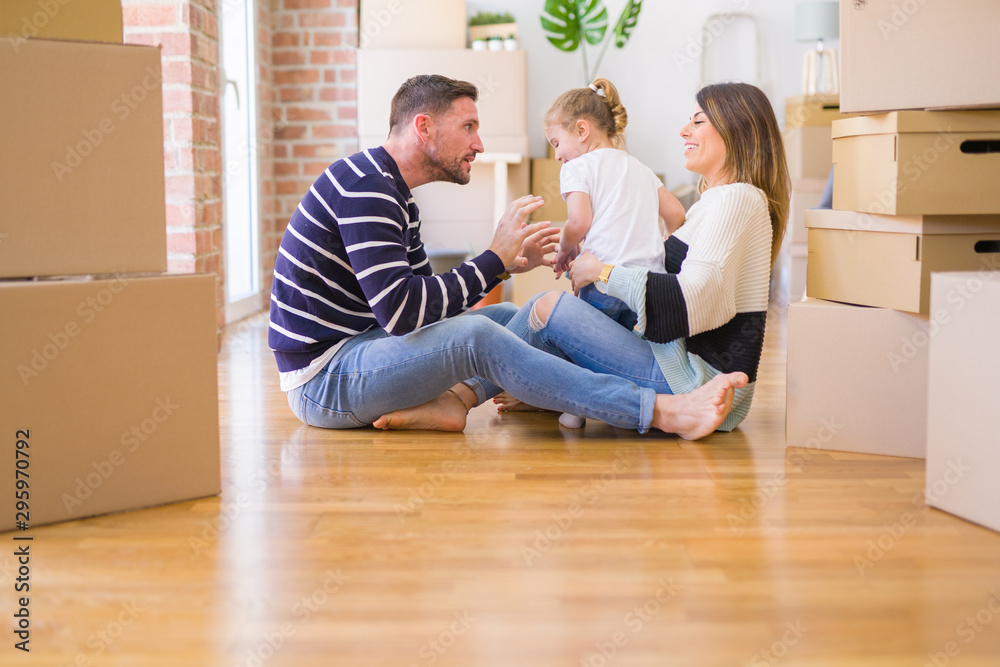 Beautiful family sitting on the floor playing with his kid at new home around cardboard boxes Beautiful family sitting on the floor playing with his kid at new home around cardboard boxes