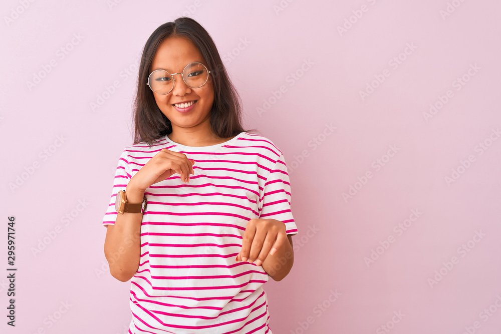 Young chinese woman wearing striped t-shirt and glasses over isolated pink background disgusted expression, displeased and fearful doing disgust face because aversion reaction. With hands raised Young chinese woman wearing striped t-shirt and glasses over isolated pink background disgusted expression, displeased and fearful doing disgust face because aversion reaction. With hands raised