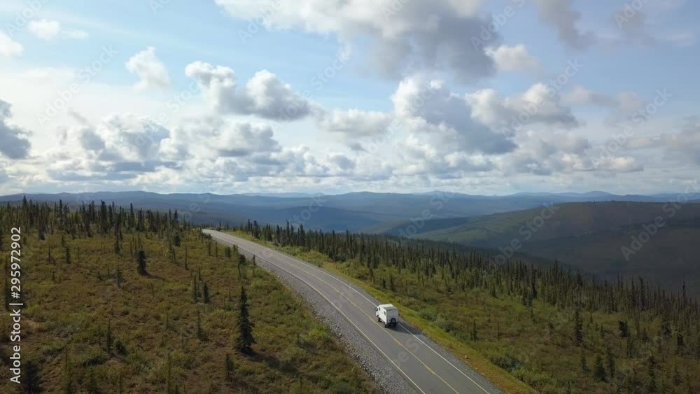 Aerial, drone shot, following a work truck, driving on a hill, at the top of the world highway, asphalt road, on hills, overlooking endless Alaskan wilderness, on a partly sunny day, in Alaska, USA Aerial, drone shot, following a work truck, driving on a hill, at the top of the world highway, asphalt road, on hills, overlooking endless Alaskan wilderness, on a partly sunny day, in Alaska, USA