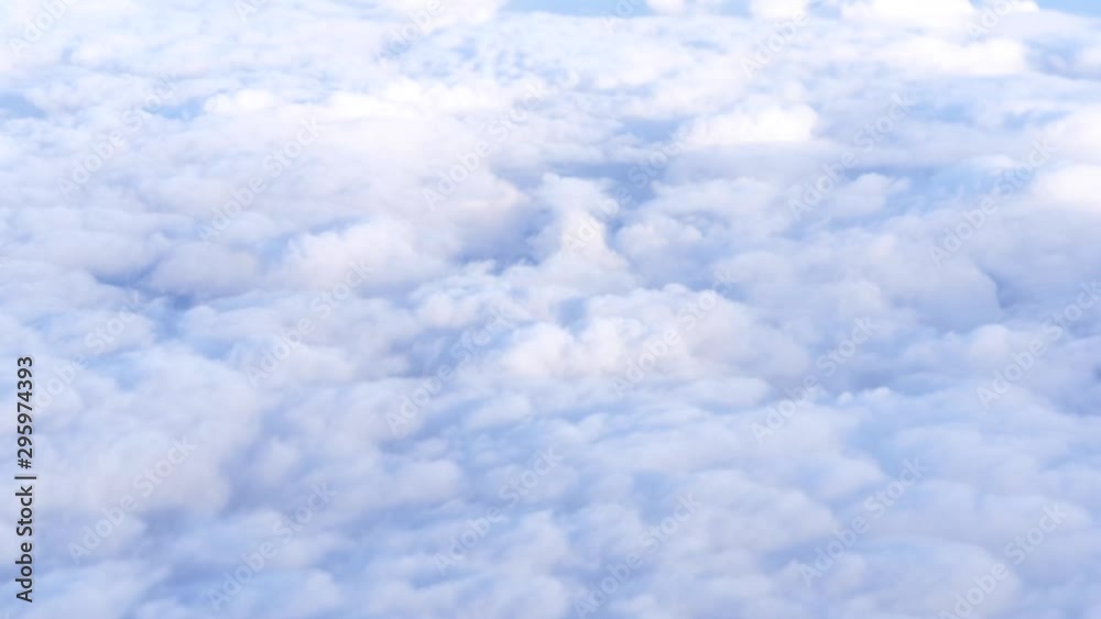 Airplane flying over fluffy cloud cover high in the sky. Gray clouds overcast the view to the ground. Airplane flying over fluffy cloud cover high in the sky. Gray clouds overcast the view to the ground.