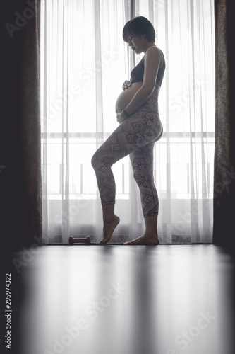 pregnant woman standing over curtain.