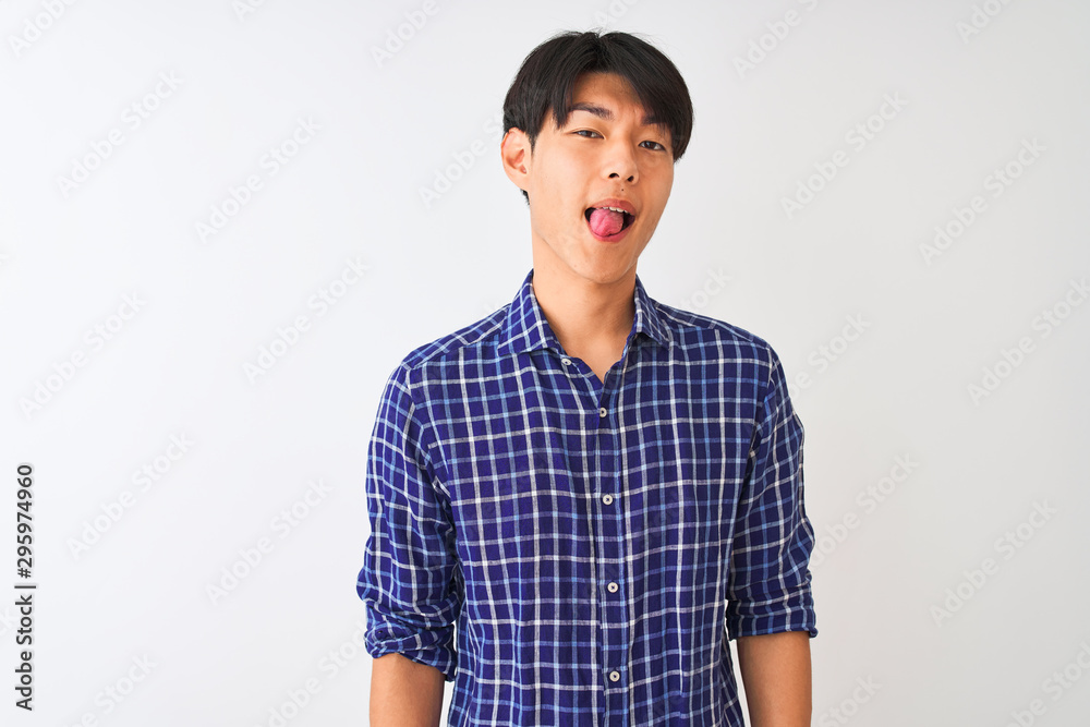 Young chinese man wearing casual blue shirt standing over isolated white background sticking tongue out happy with funny expression. Emotion concept. Young chinese man wearing casual blue shirt standing over isolated white background sticking tongue out happy with funny expression. Emotion concept.