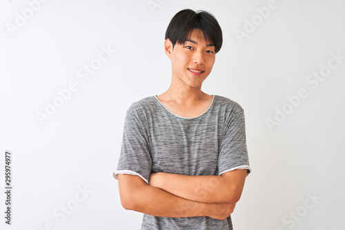 Young chinese man wearing casual t-shirt standing over isolated white background happy face smiling with crossed arms looking at the camera. Positive person.