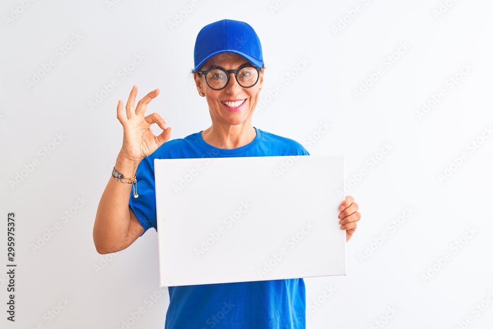 Senior deliverywoman wearing cap and glasses holding banner over isolated white background doing ok sign with fingers, excellent symbol Senior deliverywoman wearing cap and glasses holding banner over isolated white background doing ok sign with fingers, excellent symbol