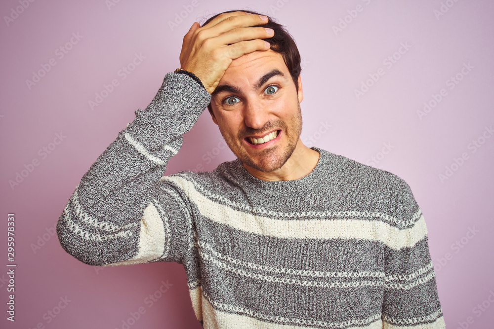 Young handsome man wearing casual striped sweater standing over isolated pink background stressed with hand on head, shocked with shame and surprise face, angry and frustrated. Fear and upset Young handsome man wearing casual striped sweater standing over isolated pink background stressed with hand on head, shocked with shame and surprise face, angry and frustrated. Fear and upset